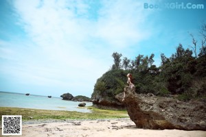 A woman sitting on a rock on the beach.