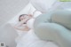 A pregnant woman laying on a bed with white sheets.